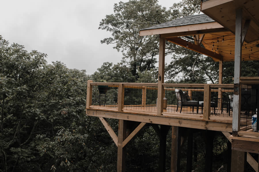 Elevated timber deck with cable railings over a wooded mountain slope