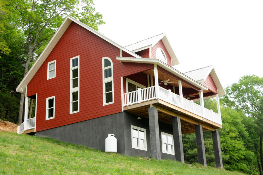 Great Room Farmhouse, red farmhouse with white metal roof and covered porches