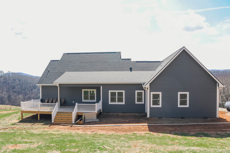 Long-range view home exterior with gray siding and a covered deck overlooking the mountains