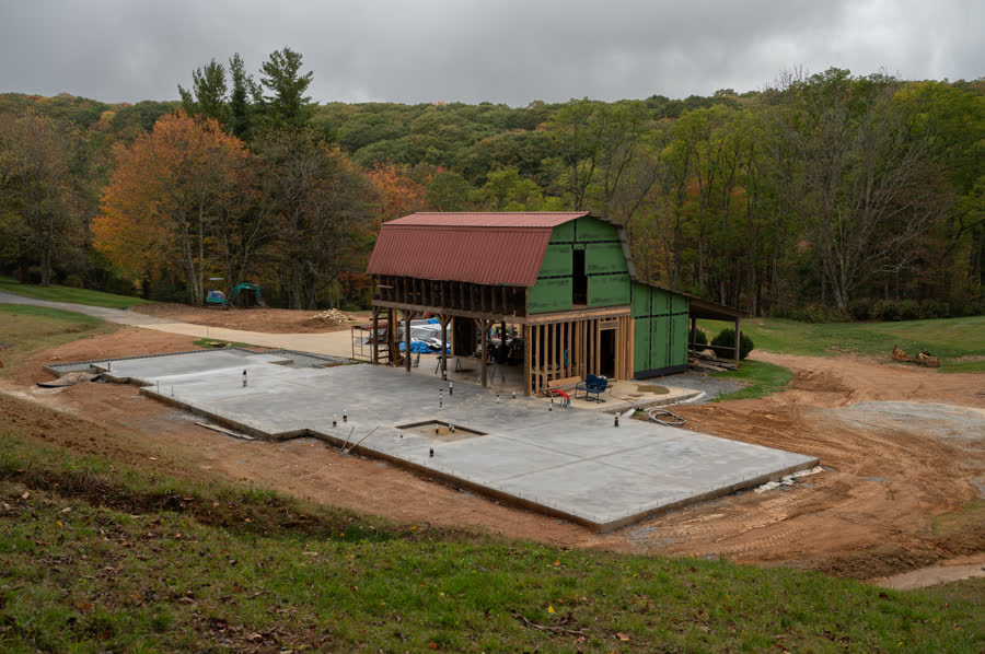 Foundation and slab work in progress with the original barn behind