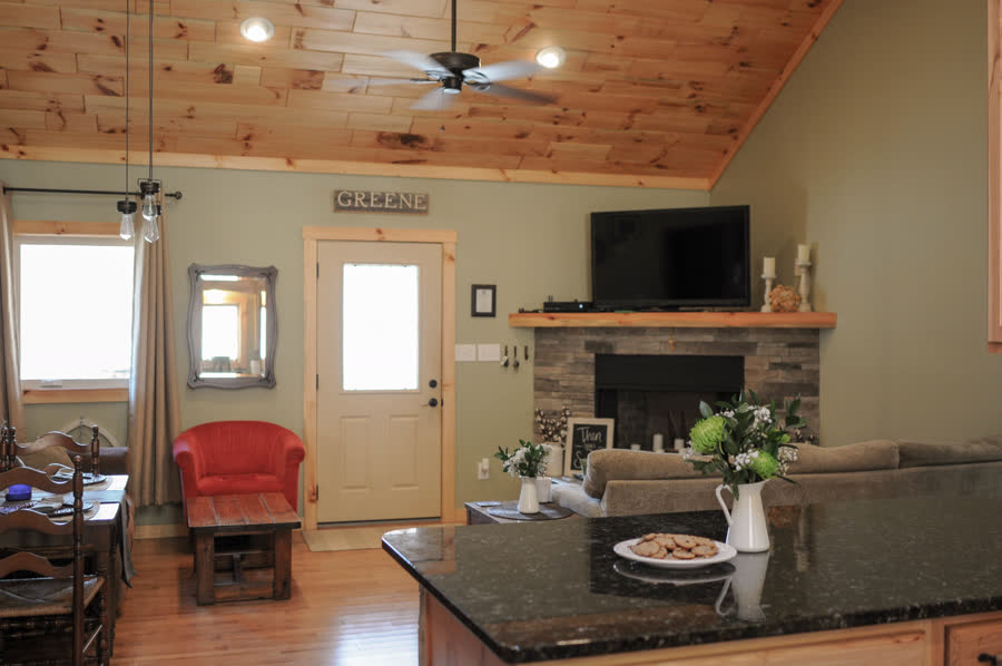 Home addition with vaulted pine ceiling and stone fireplace by ARCH Home Crafters